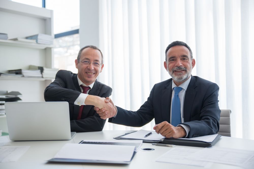 Two executives shaking hands across a desk